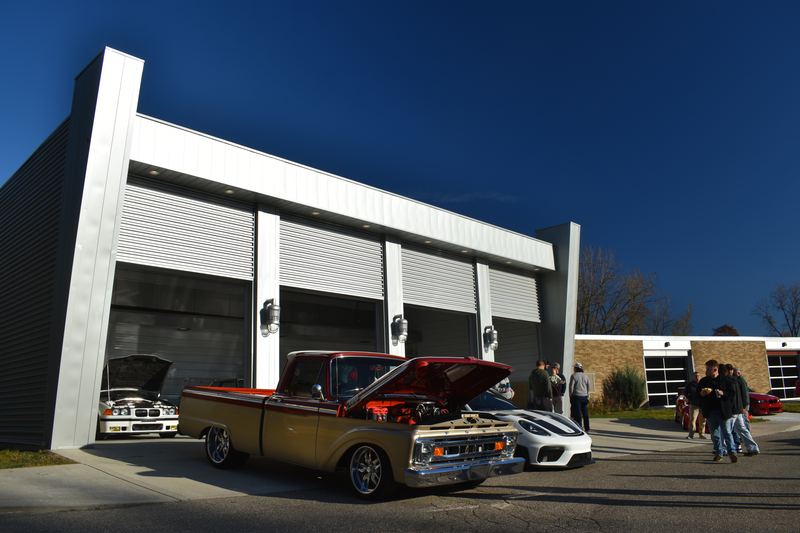 A classic pickup with its hood up in front of the club building's new garage doors.
