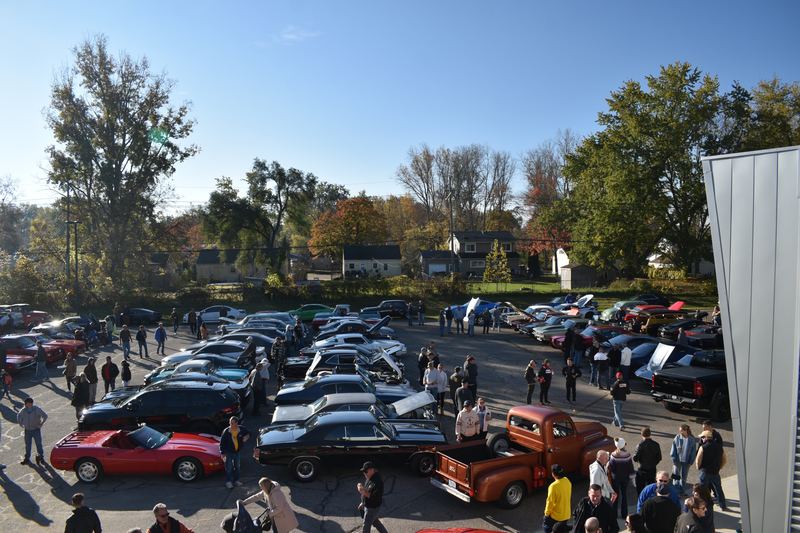 A packed lot with a red Ferrari and an orange classic pickup in front.