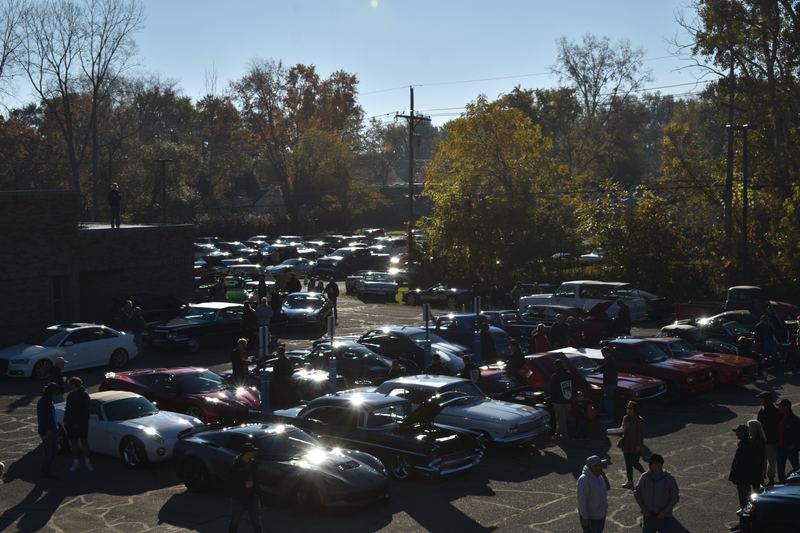 Sun glinting off a lot full of cars, seen from above the crowd.