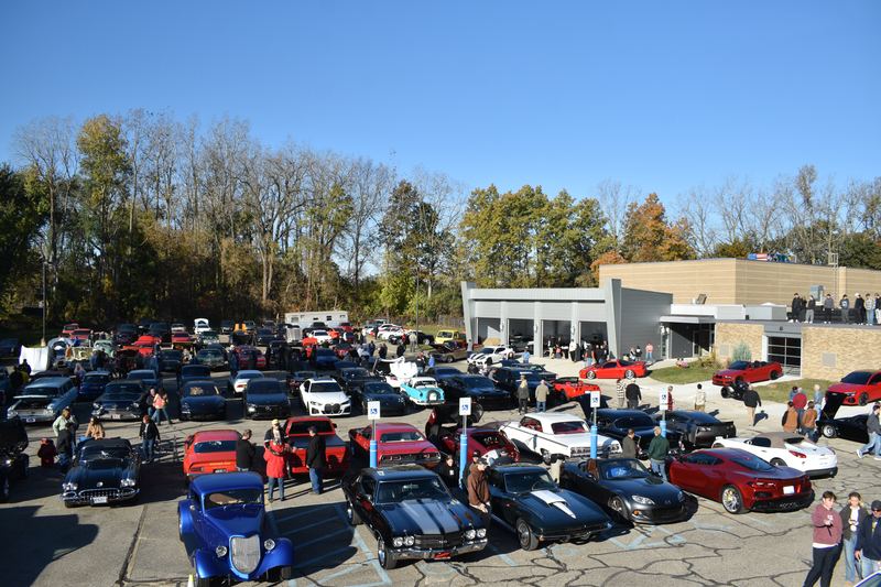 Rows of cars filling the lot, with the club building and its garage doors behind.