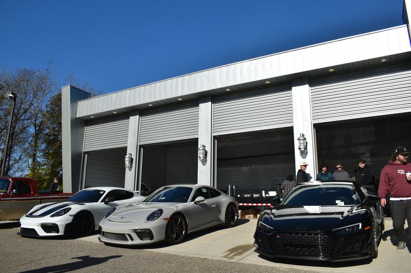 A Porsche 911 GT3 RS, a silver 911 and a black Audi R8 parked at the garage doors.