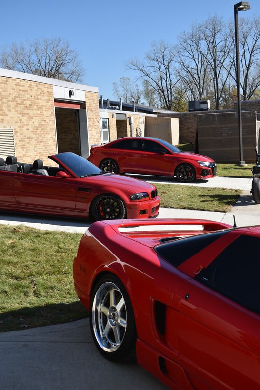 A red convertible and a red Acura NSX parked by the building.